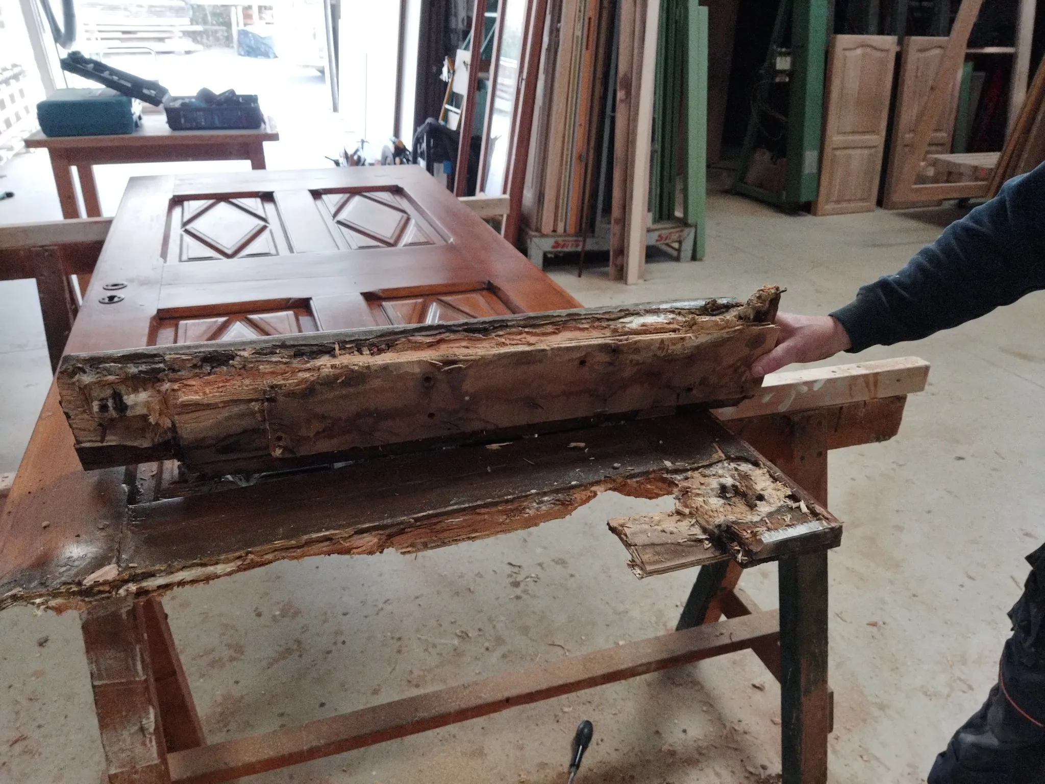 Porte en bois en cours de restauration par un ébéniste, montrant des détails de réparation et de remise en état.